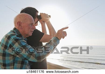 Stock Photograph - Old man and grandson looking out to sea. Fotosearch