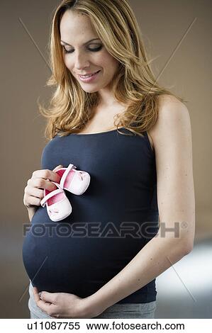 Pregnant woman holding girl baby shoes View Large Photo Image Stock Photography - Pregnant woman holding girl baby shoes. Fotosearch