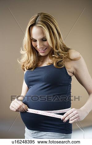 Stock Photography - Pregnant woman measuring belly. Fotosearch