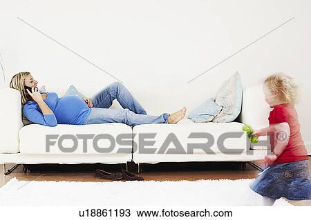 Stock Image - Pregnant woman on phone with toddler. Fotosearch