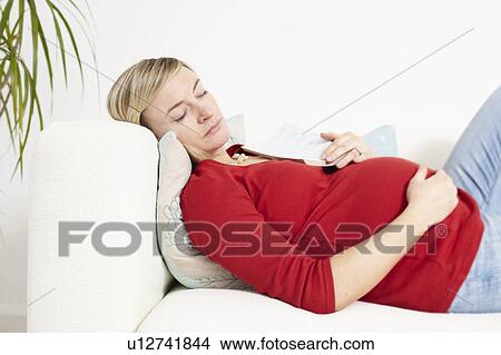 Picture - Pregnant woman sleeping on sofa. Fotosearch