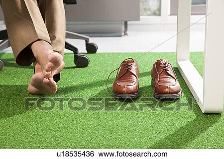 Stock Photograph - Relaxed feet on a green office carpet. Fotosearch