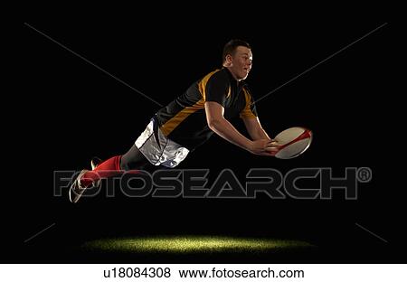 Stock Photo - Rugby player diving an throwing ball. Fotosearch
