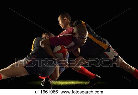 Stock Photograph - Rugby player tackled by two opponents. Fotosearch
