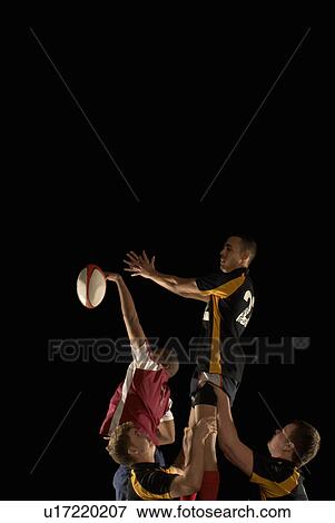 Stock Photo - Rugby players competing for ball in air. Fotosearch