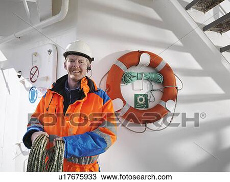 Stock Image - Sailor holding rope on deck. Fotosearch
