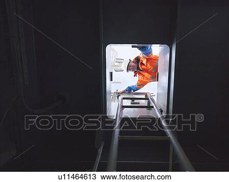 Stock Image - Sailor looking through hatch. Fotosearch