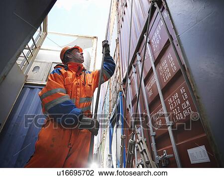 Stock Image - Sailor pulling a rope in cargo bay. Fotosearch
