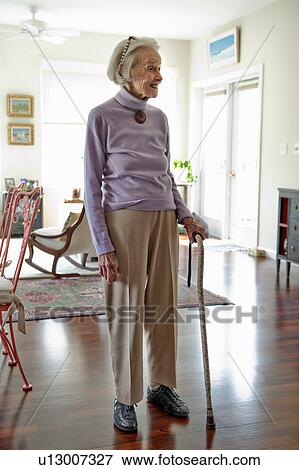 Senior woman standing in her living room View Large Photo Image Stock Photo - Senior woman standing in her living room. Fotosearch