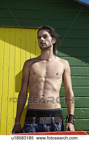 Shirtless man standing by beach hut View Large Photo Image Stock Photography - Shirtless man standing by beach hut. Fotosearch