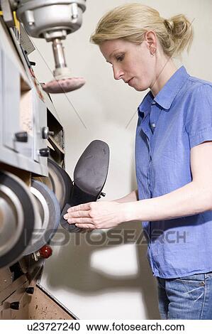 Stock Image - Shoemaker grinding the sole of the shoe. Fotosearch