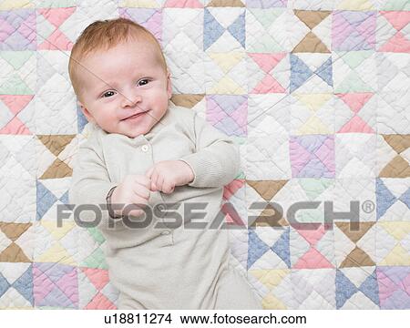 Picture - Smiling baby on quilt. Fotosearch
