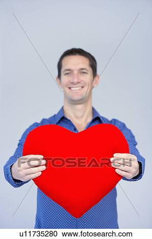 smiling man showing a big red heart View Large Photo Image Stock Image - smiling man showing a big red heart. Fotosearch