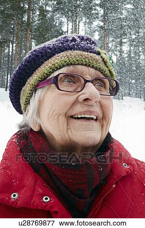 Stock Photo - Smiling older woman watching snow fall. Fotosearch