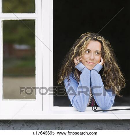 Stock Photography - Smiling woman looking out window. Fotosearch
