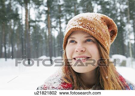 Smiling young woman watching snow fall View Large Photo Image Stock Image - Smiling young woman watching snow fall. Fotosearch