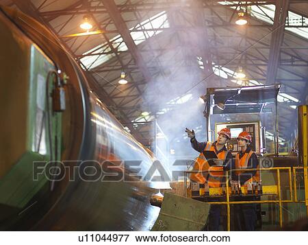 Stock Photo - Steel Engineers Inspecting Lathe. Fotosearch