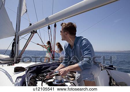 Stock Image - Team setting sail on yacht. Fotosearch
