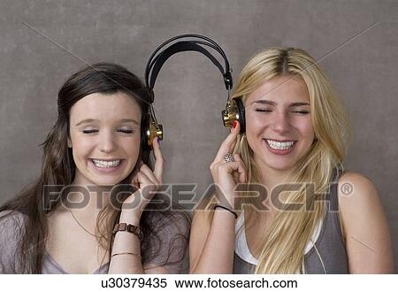 Stock Photography - Teen friends share headphones. Fotosearch