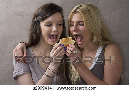 Stock Image - Teen friends share sandwich. Fotosearch