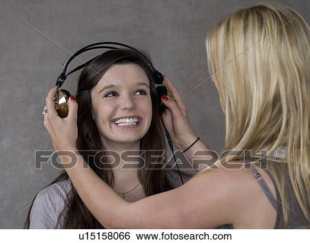 Stock Photograph - Teen girls put on headphones. Fotosearch