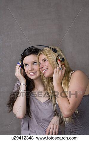 Stock Photo - Teen girls share headphones. Fotosearch