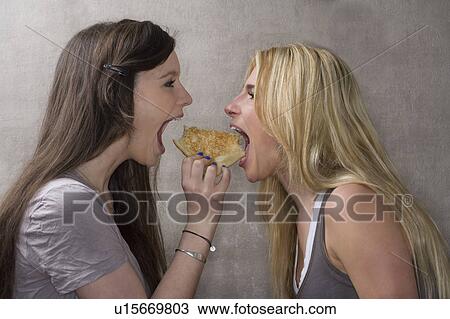 Stock Image - Teen girls share sandwich. Fotosearch