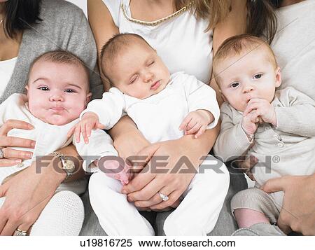 Stock Photography - Three babies in mothers arms. Fotosearch