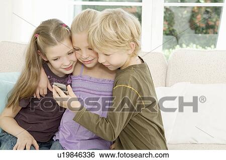 Stock Photograph - Three children looking at a mobile phone. Fotosearch