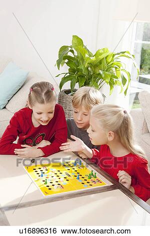 Three children playing a board game View Large Photo Image Stock Photograph - Three children playing a board game. Fotosearch