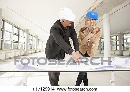 Picture - Two architects checking plans of site. Fotosearch