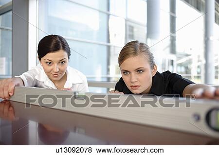Two businesswomen using spirit level View Large Photo Image Stock Photo - Two businesswomen using spirit level. Fotosearch
