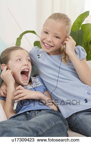 Stock Image - Two girls listening to an MP3 player. Fotosearch