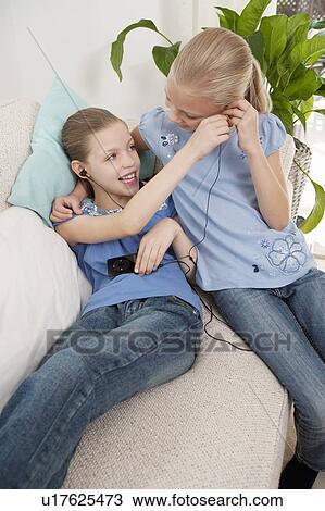 Stock Image - Two girls listening to an MP3 player. Fotosearch
