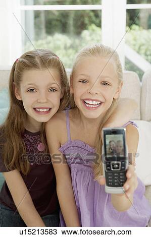 Stock Image - Two girls show their picture on a mobile. Fotosearch