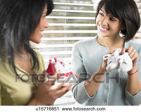 Stock Image - Two mothers comparing baby shoes. Fotosearch