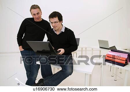 Two relaxed business men look at laptop View Large Photo Image Stock Image - Two relaxed business men look at laptop. Fotosearch