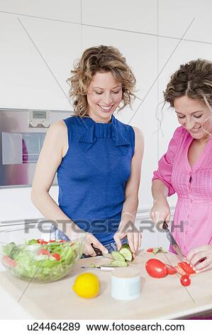 Two woman cutting vegetables in kitchen View Large Photo Image Stock Photo - Two woman cutting vegetables in kitchen. Fotosearch
