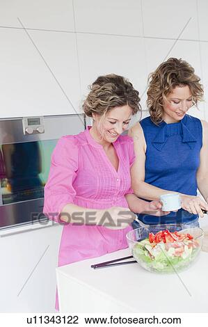 Stock Image - Two woman preparing salad in kitchen. Fotosearch