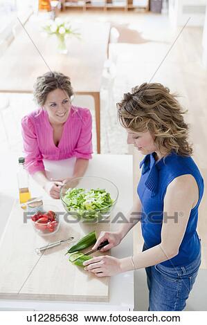 Stock Photo - Two woman preparing salad in kitchen. Fotosearch