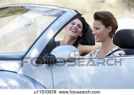 Stock Photo - Two women laughing in a convertible car. Fotosearch