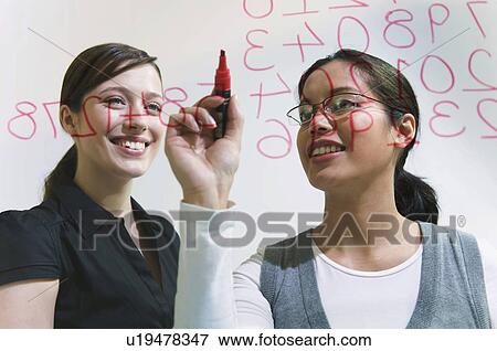 Two women work on figures on glass wall View Large Photo Image Stock Photo - Two women work on figures on glass wall. Fotosearch