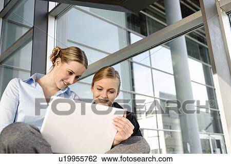 Stock Image - Two young business woman with laptop. Fotosearch
