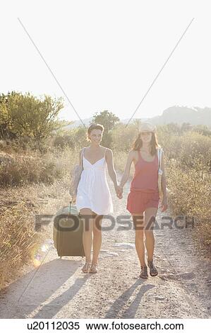 Two young women walking along a lane View Large Photo Image Stock Photography - Two young women walking along a lane. Fotosearch
