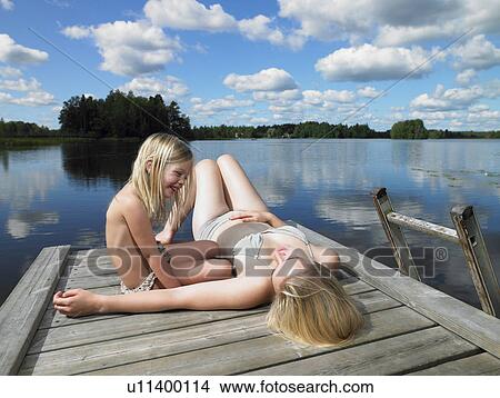 Woman and girl tanning on a dock View Large Photo Image Picture - Woman and girl tanning on a dock. Fotosearch