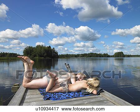Woman and girl tanning on a dock View Large Photo Image Stock Photo - Woman and girl tanning on a dock. Fotosearch