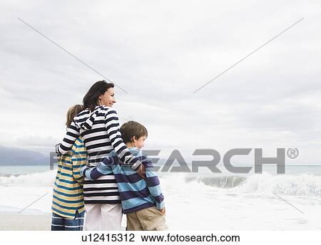 Stock Image - Woman and two boys looking out to sea. Fotosearch