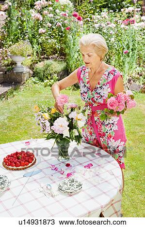 Stock Image - woman arranging flowers.. Fotosearch