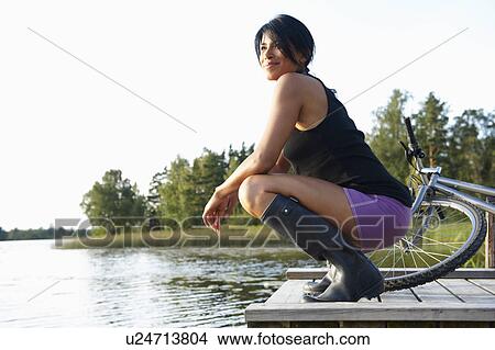 Picture - Woman at the end of a dock, with bike. Fotosearch