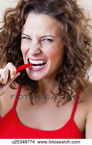Picture - Woman Biting Chili. Fotosearch